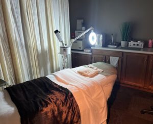 - Results Salon and Spa in Kingsport, TN A treatment room with a massage table covered in white and brown linens, a magnifying lamp, towels, and cabinets with spa equipment. - Results Salon and Spa in Kingsport, TN